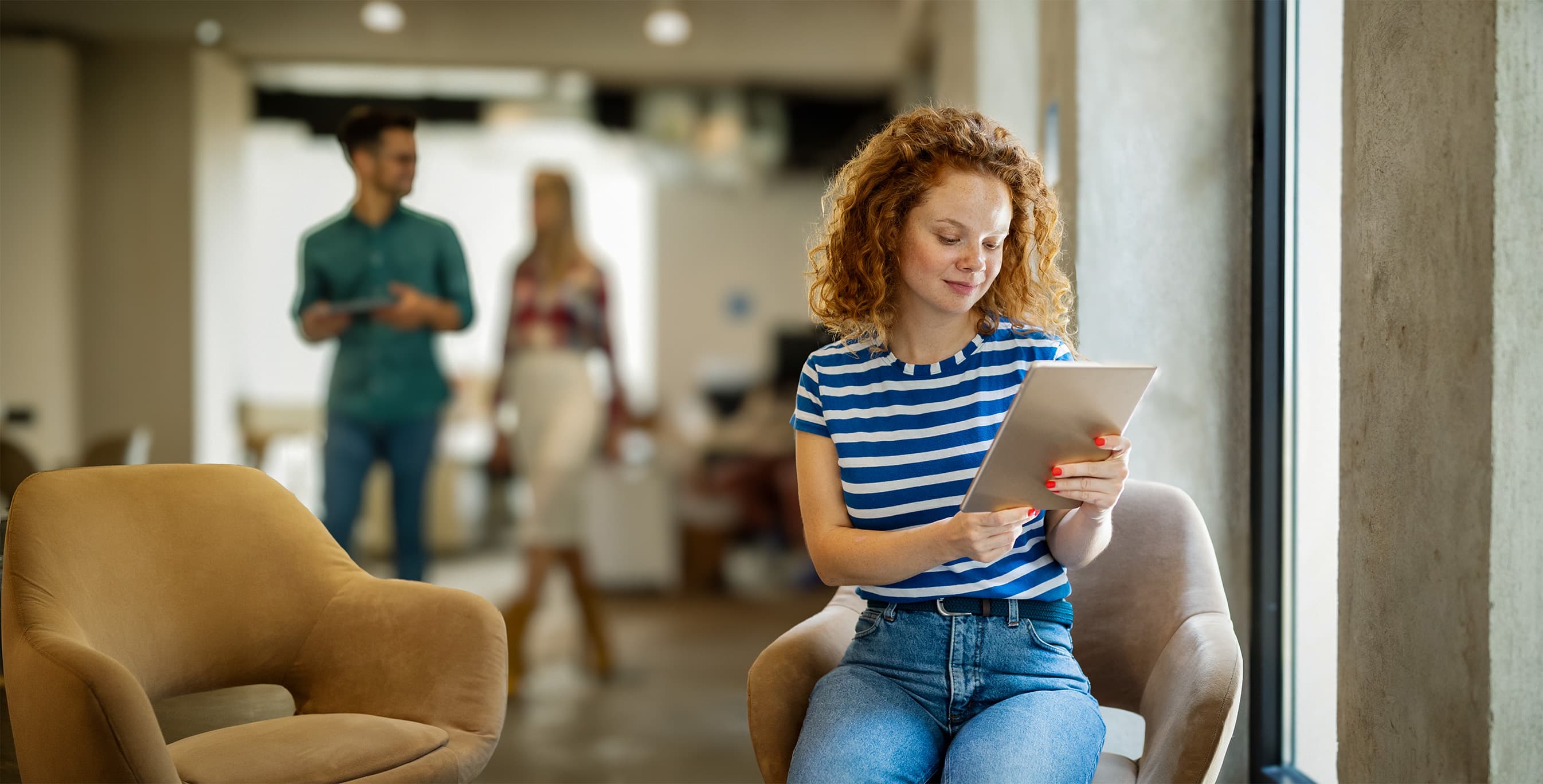 A woman using a tablet in a bright lounge